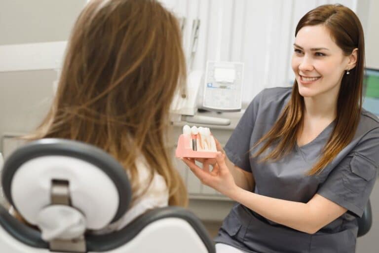dental assistant showing off dental implant model, Are Dental Implant Procedures A Comprehensive Tooth Replacement Option?