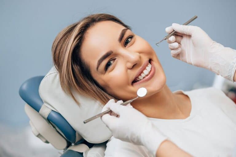 dental implant patient smiling during exam, With Dental Implants, Can I Have A Biocompatible New Smile?