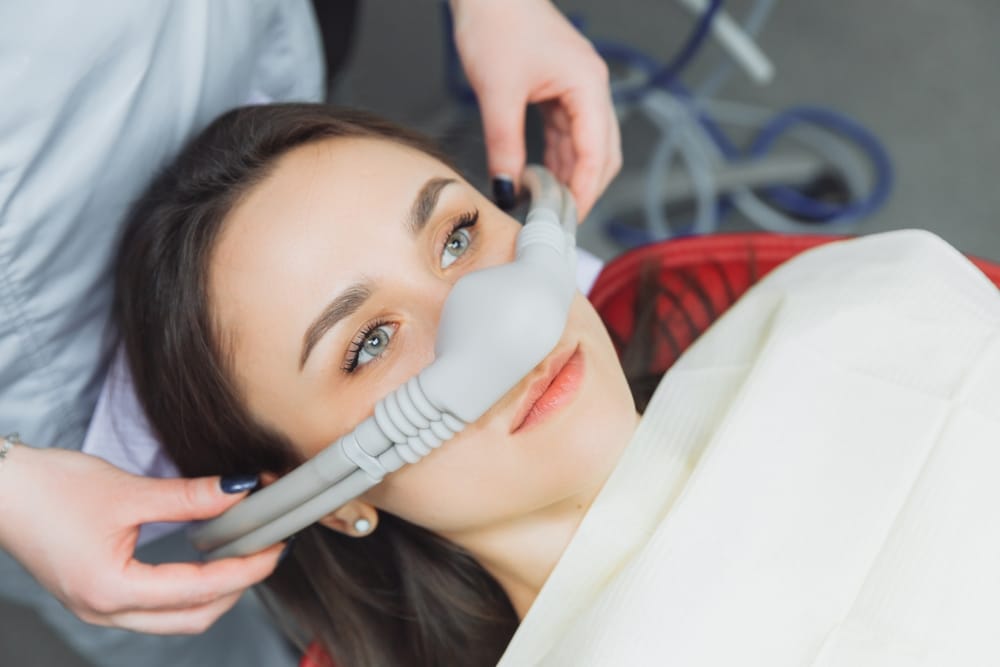 A dentist puts inhalation sedative mask on their patient