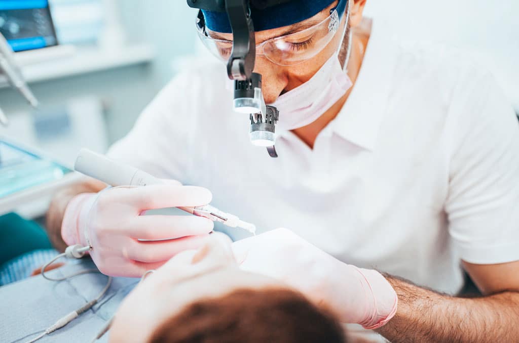 Dentist cleans tooth canals of patient