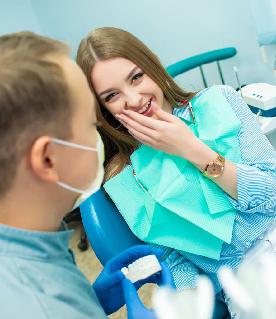 A happy female patient and a male dentist wearing a protective mask