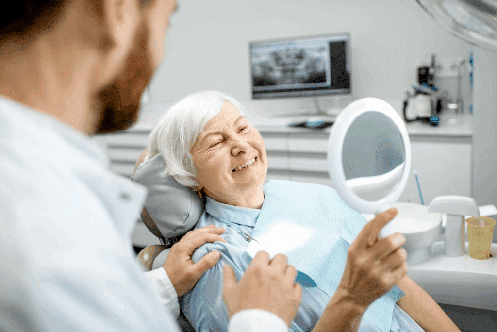 Happy older woman looking in mirror admiring her teeth