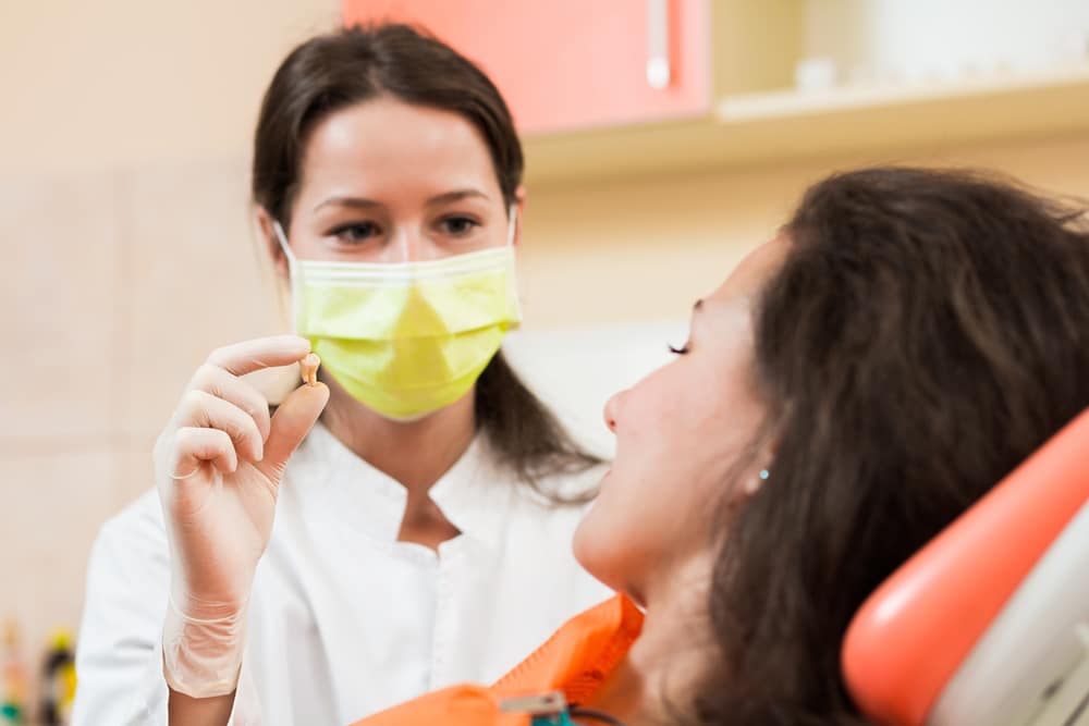 A dentist showing an extracted tooth to a patient