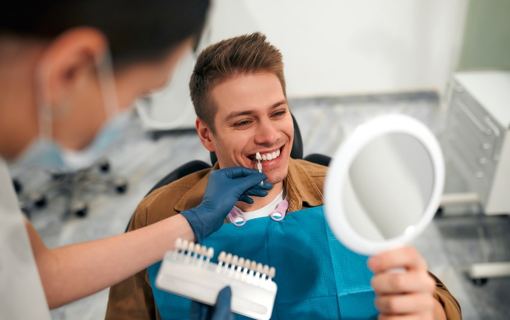 A dentist checking which color of the veneer is right for his patient